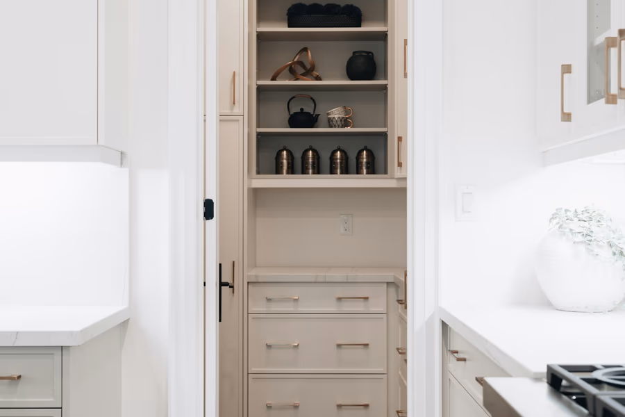 A tall kitchen storage run with open shelving above a bank of three deep drawers, the cabinetry carried up to the ceiling
